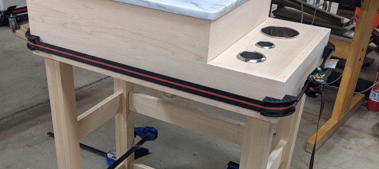 A web clamp holding a boxed piece together. Tightens like a tie-down.